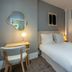 Makom Pereire in Paris: compact guest room with a neatly made bed, desk, chair, and warm bedside lamp