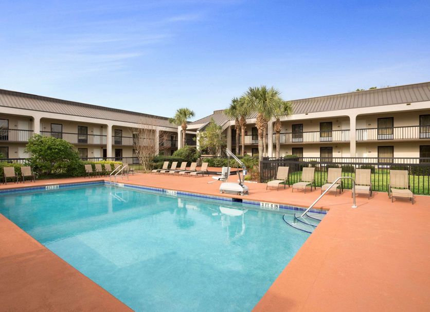 Days Inn by Wyndham Jacksonville Airport pool courtyard with palm trees and lounge chairs in Jacksonville