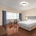 Beijing Hwa Apartment Hotel guest room with king bed, window seating and polished wood floors in Beijing