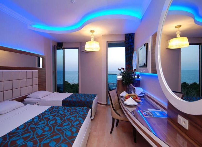 Grand Zaman Beach Hotel Alanya guest room with twin beds, balcony sea view, and illuminated ceiling