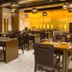 Hotel Le Temps Fort in Tiruchirappalli dining room with dark wood tables, chairs and hanging globe lights