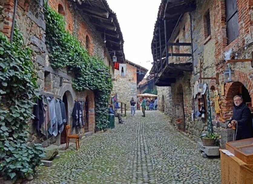 Hotel Michelangelo in Biella, cobblestone village street between ivy-covered stone buildings