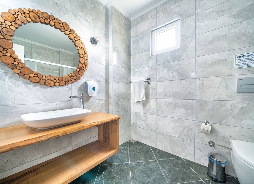 Dedeminn Garden Hotel bathroom in Göcek with vessel sink, wood counter, tiled walls, and toilet