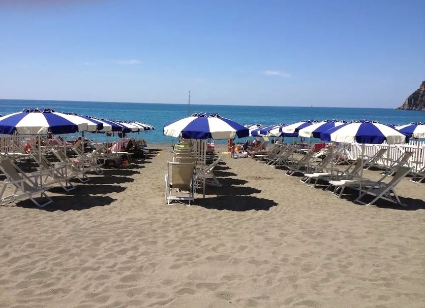 Tigullio Camping & Resort in Sestri Levante beach with rows of blue-and-white umbrellas and loungers