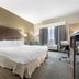 Best Western Brockport Inn & Suites guest room with king bed, desk, chair and window seating in Brockport