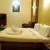 Fabhotel Prime Chennai Deluxe room with neatly made bed, towel swan, wall-mounted TV and seating