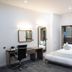 Atrium Hotel Heathrow in Hounslow guest room with king bed, desk, chair and full-length mirror