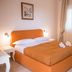 Agriturismo I Pozzetti in Fasano bedroom with orange bed, mirror, chair and window light