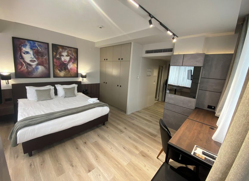 Queen's Hotel - Zebra Centre, Skopje: modern hotel room with king bed, desk, wardrobe and wood flooring