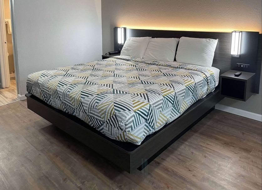 Studio 6 Vicksburg, MS guest room with king bed, patterned bedding and bedside lamps