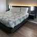 Studio 6 Vicksburg, MS guest room with king bed, patterned bedding and bedside lamps
