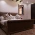 Zifan Hotel & Suites Karachi guest room with king bed, patterned rug, mirror and sofa