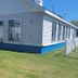 Mackinaw Budget Inn in Mackinaw City, exterior of a white motel-style building with blue base and lawn