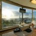 Viewtower Resort in Jeju City room with corner sea and city views, bed, and small table by large windows