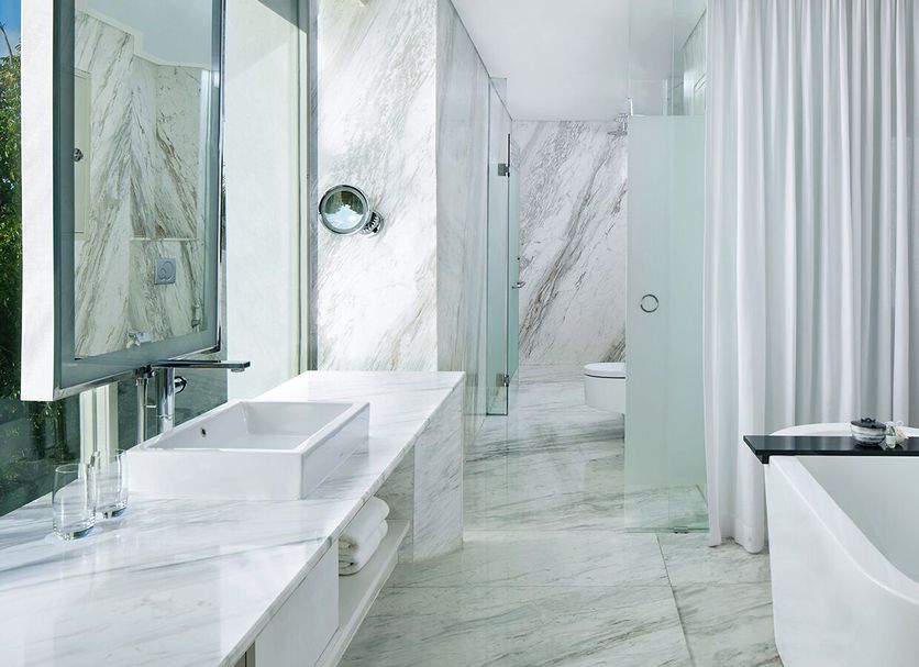 The Stones Hotel - Legian Bali bathroom in Kuta with marble vanity, glass shower, and soaking tub