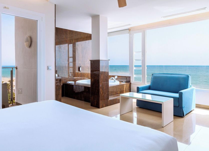 Playasol in Roquetas de Mar: bright sea-view room with balcony, blue sofa, and bathtub