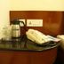 Fabhotel Prime Chennai Deluxe bedside table with phone, kettle and glasses in Chennai