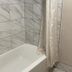 Bear Mount Inn & Suites in Pigeon Forge bathroom with a white bathtub and marble-look tile walls