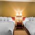 Quality Suites New Iberia twin beds with bedside lamp and nightstand in guest room