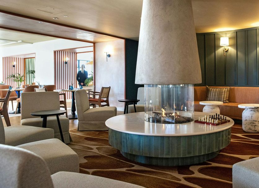 The Relais Cooden Beach lounge in Bexhill-on-Sea with circular fireplace, seating and bookshelves