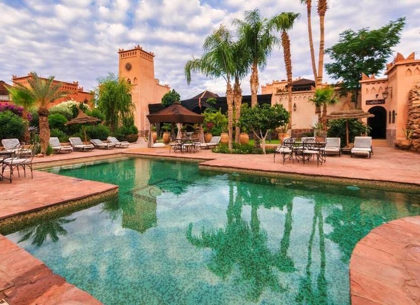 Ksar Ighnda in Aït Ben Haddou with a courtyard pool, palm trees and lounge chairs