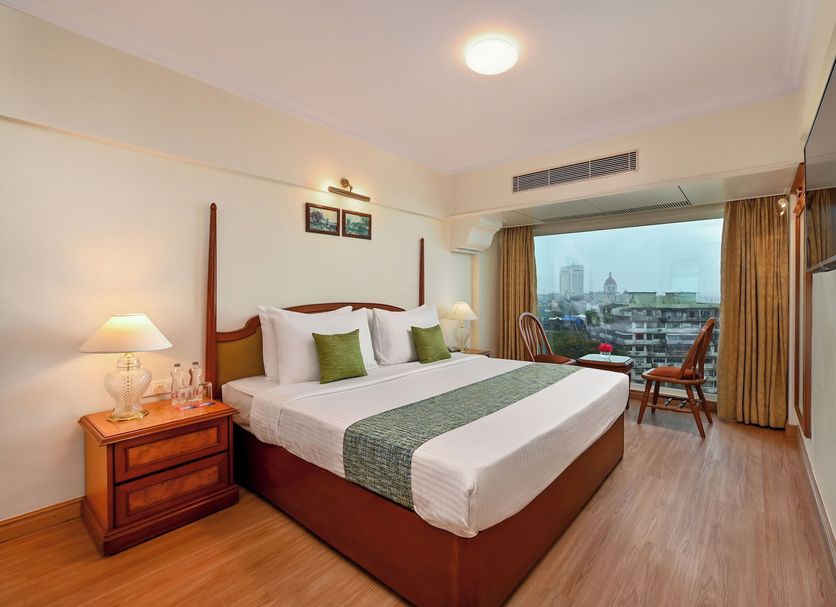 Fariyas Hotel in Mumbai guest room with city view, king bed, wall-mounted TV and seating area