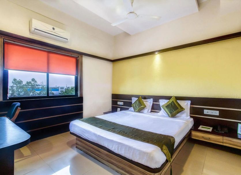 Hotel Golden Treat Indore room with double bed, window view, desk and wall-mounted air conditioner