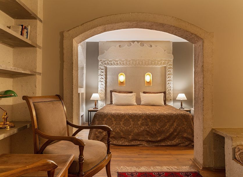 Heybe Hotel & Spa in Göreme: cozy arched cave-style bedroom with king bed, bedside lamps, and armchair