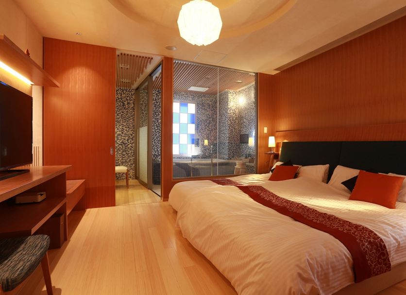 Honjin Hiranoya Kachoan in Takayama: warm guest room with king bed and glass-enclosed bath area