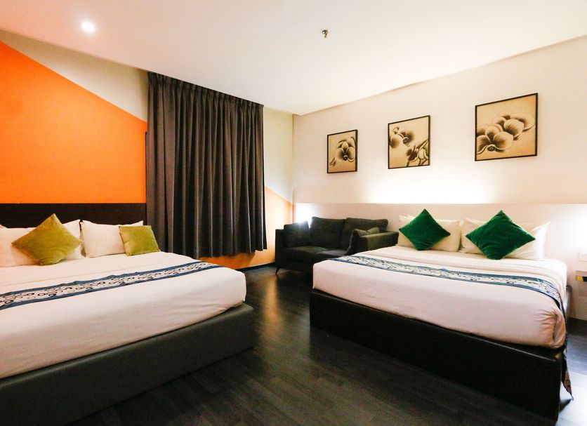 Golden Roof Hotel Ampang Ipoh in Ipoh: guest room with two beds, black sofa, and orange accent wall