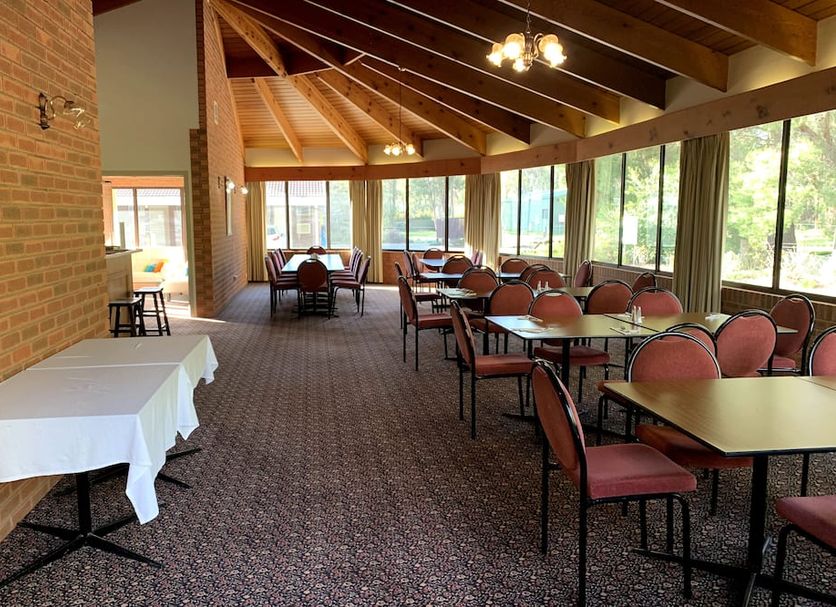 Kingswood Motel in Tocumwal dining room with tables, chairs, brick wall and large windows