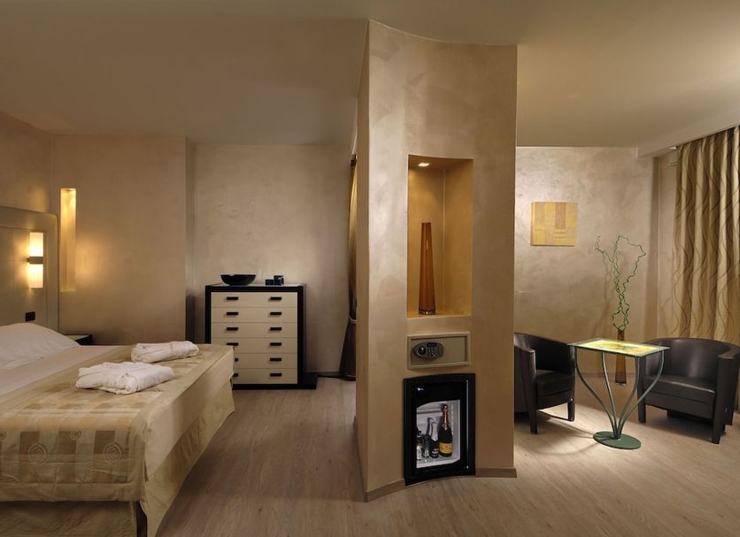 Hotel La Cartiera in Vignola guest room with bed, seating area, and modern fireplace niche