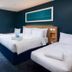 Travelodge London Kingston Upon Thames room with two beds, teal walls, and a window view in Kingston upon Thames