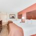 Baymont by Wyndham Midland Airport guest room with two beds, TV, dresser and coral accent wall