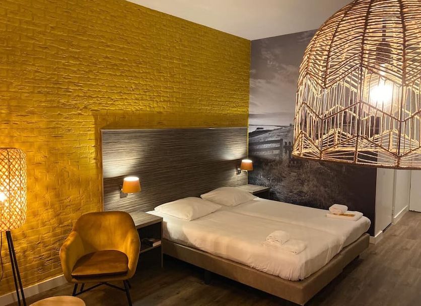 Strandhotel Vigilante in Makkum guest room with double bed, textured gold wall and woven pendant lights