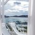 Rhenia Hotel in Tourlos with balcony sea view, lounge chairs, and harbor boats beyond glass railing