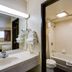 Skylight Inn Cleveland - Willoughby bathroom with sink, mirror, towels, and adjoining tub-shower area