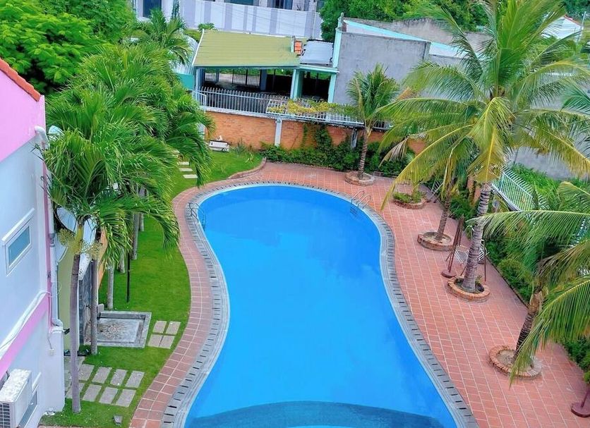 Volga Apartment Hotel in Mũi Né with a curved outdoor pool surrounded by palm trees
