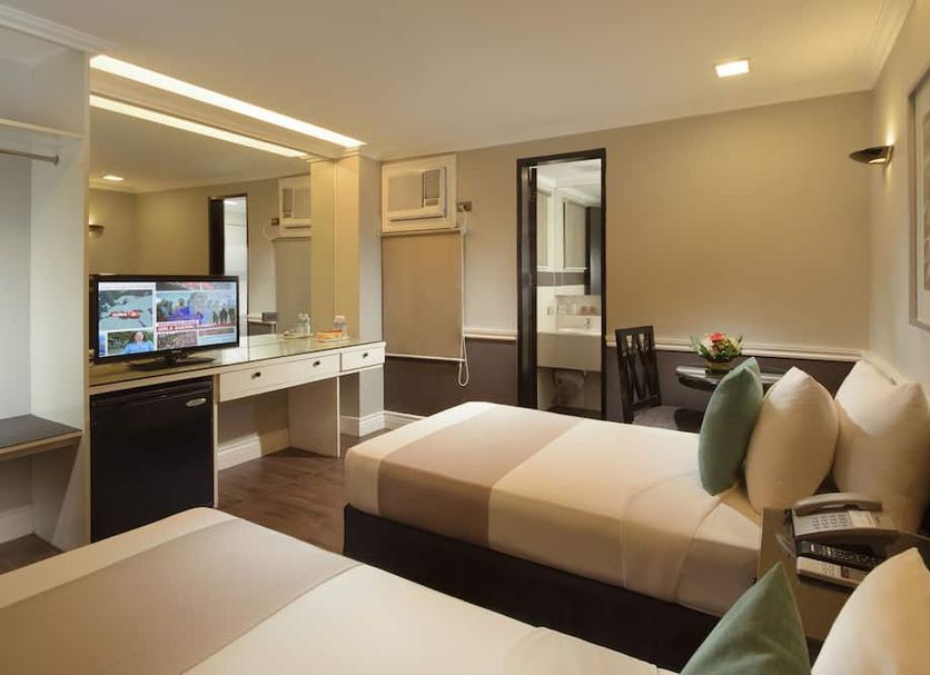The MetroCentre Hotel and Convention Center room in Tagbilaran with twin beds, desk, and TV