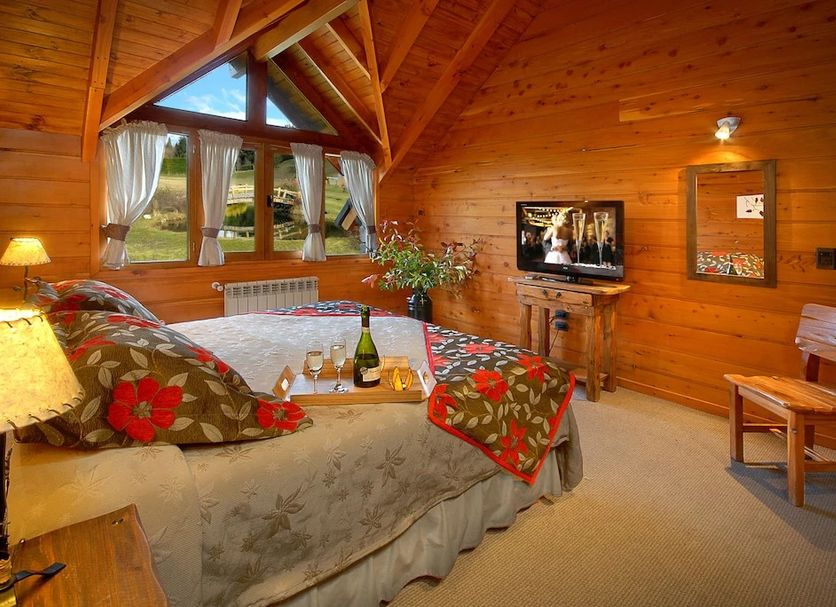La Estancia Cabanas in Villa La Angostura: cozy wooden cabin bedroom with vaulted ceiling and mountain view