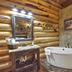 Hibernation Station in West Yellowstone bathroom with freestanding tub, log walls, and rustic vanity