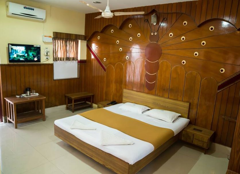 Hotel Chanma International, Coimbatore room with double bed, wood-paneled wall and wall-mounted TV