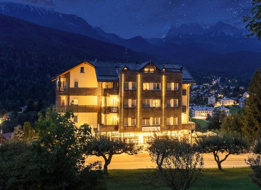 Th Cadore - Hotel Antelao in Borca di Cadore at night with glowing balconies and mountain backdrop