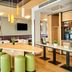 B&B Hotel Frankfurt City-Ost lobby with tables, green stools, wall art and TV in Frankfurt am Main