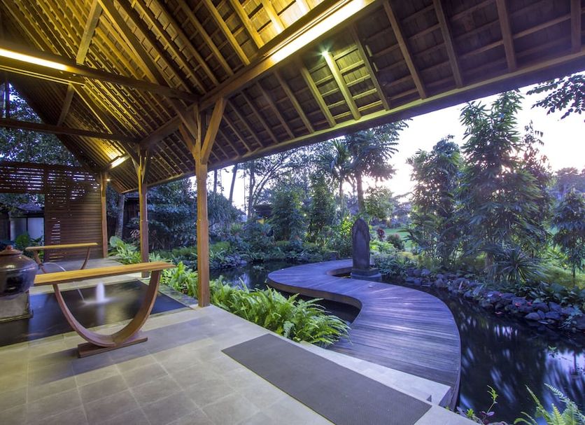 Kajane Yangloni Ubud open-air pavilion with curved wooden deck over a lush garden pond