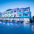 Apartamentos Sal Rossa in Sant Josep de sa Talaia with a lit outdoor pool and white beachfront building at dusk