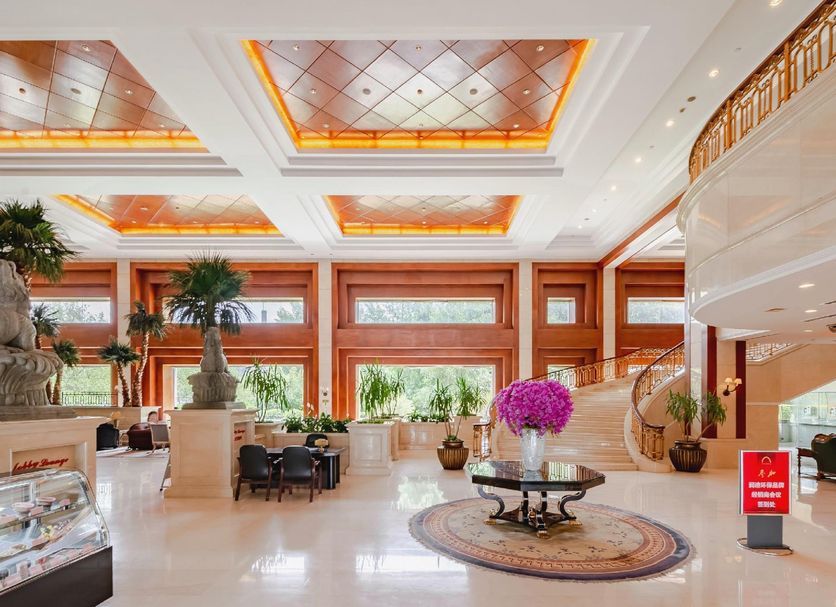 Fuhong International Hotel in Liaoyang lobby with grand staircase, skylit ceiling, and potted plants