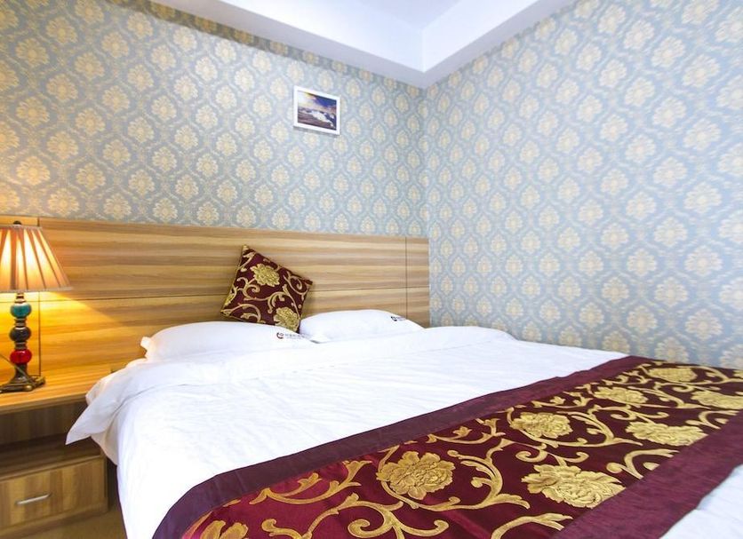Center Of City Creo Hotel in Yanbian guest room with double bed, bedside lamp, and patterned wallpaper