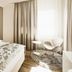 Hotel Uzwil guest room with bed, large window, modern chair and side table in Uzwil