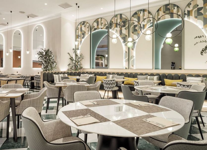 Ilunion Les Corts Spa in Barcelona dining room with arched mirrors, round tables, and upholstered chairs